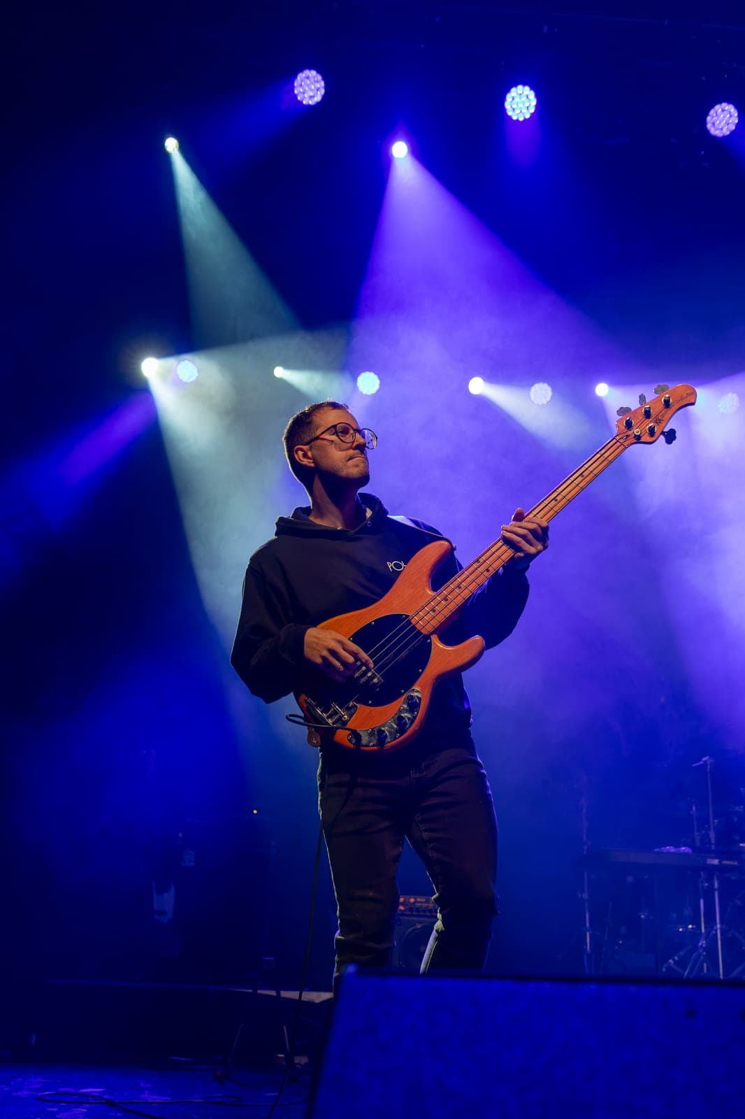 Bassist Tyler Emond works an orange bass beneath a starburst of blue stage lights in Maya Killtron's band at the Danforth Music Hall