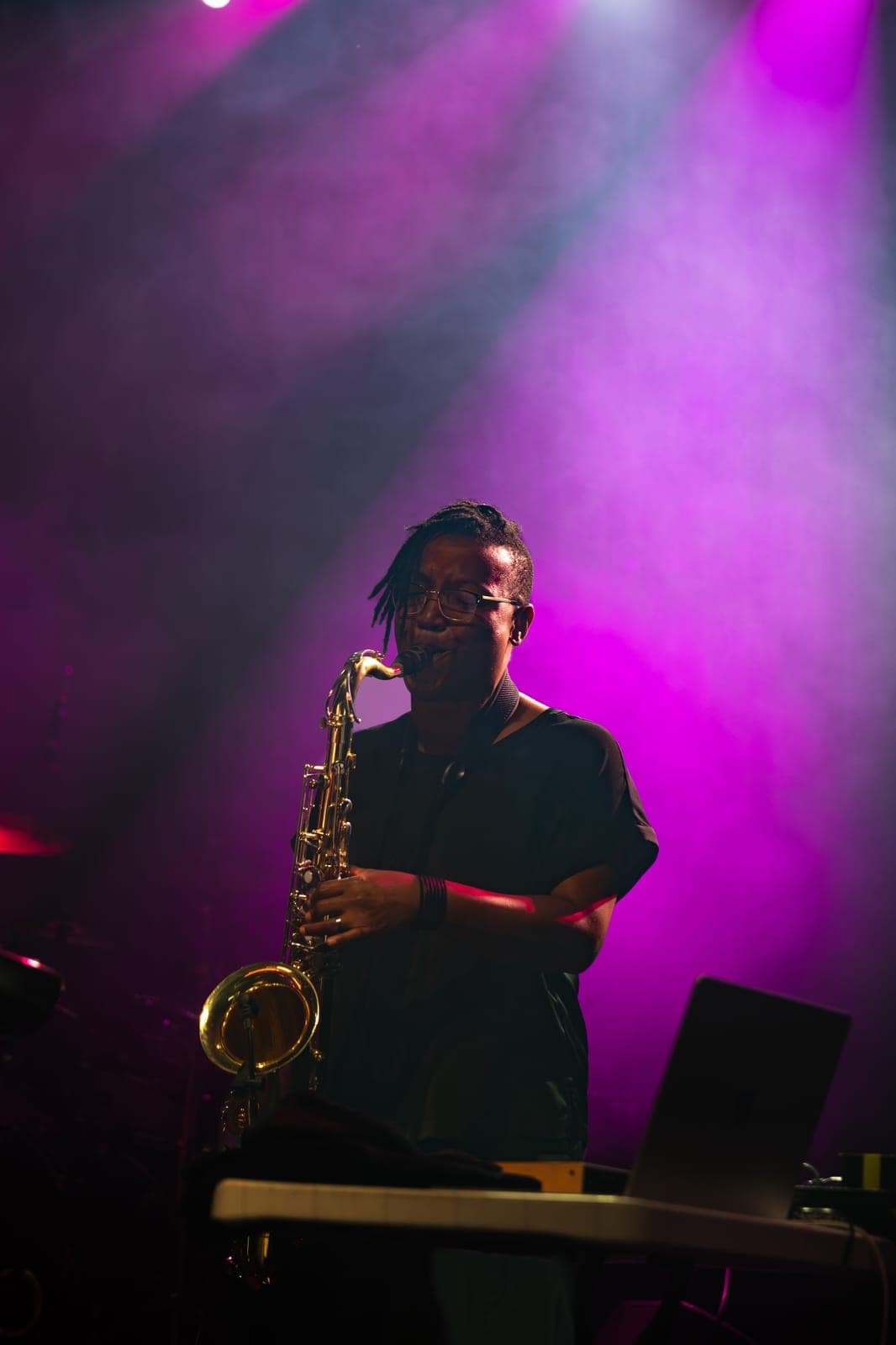 La-Nai Gabriel plays saxophone in Maya Killtron's band under magenta light and drifting haze