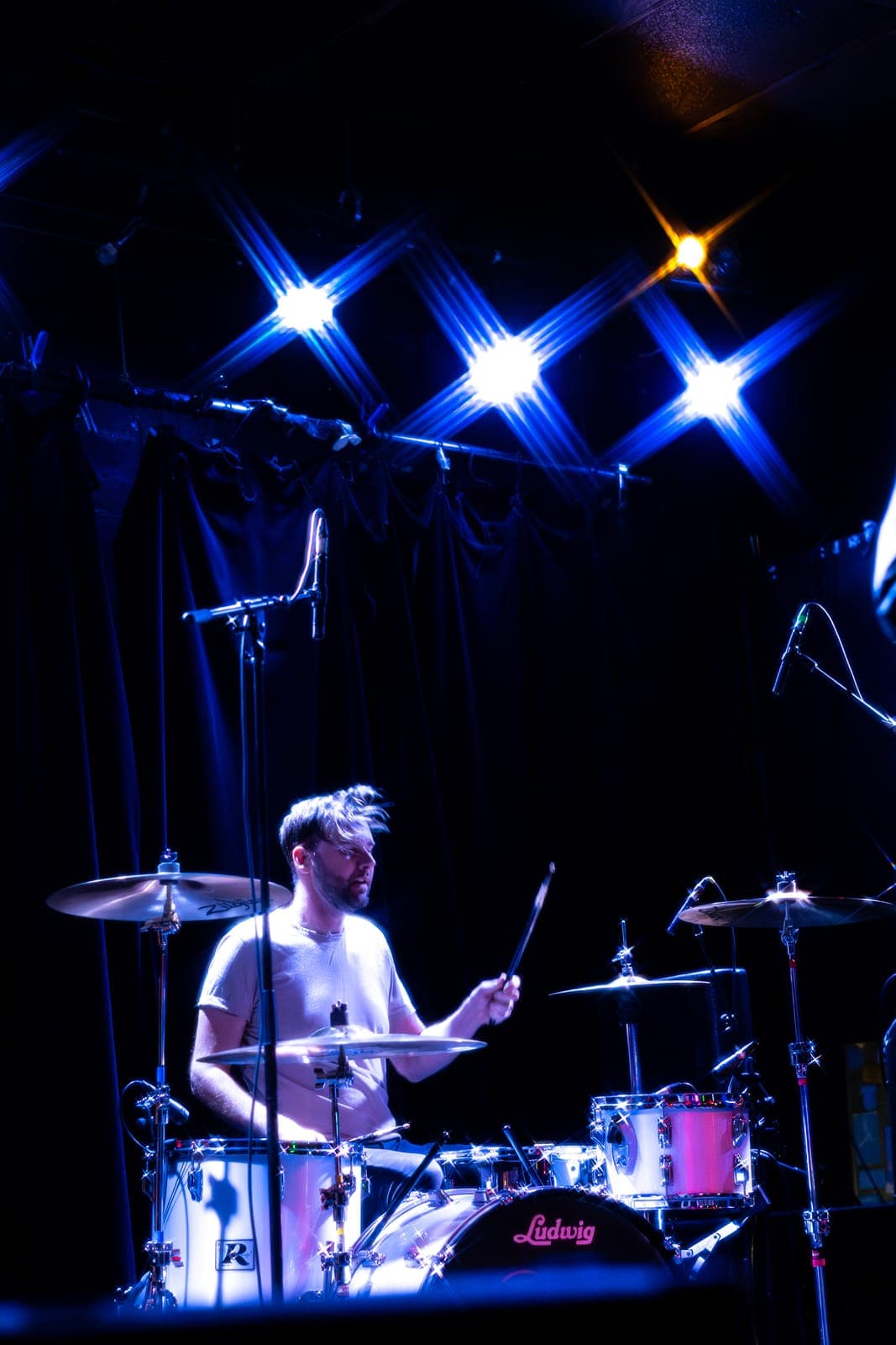 The Cribs' Ross Jarman, hair flying, strikes mid-beat behind his Ludwig kit under blue starburst lights at Lee's Palace in Toronto