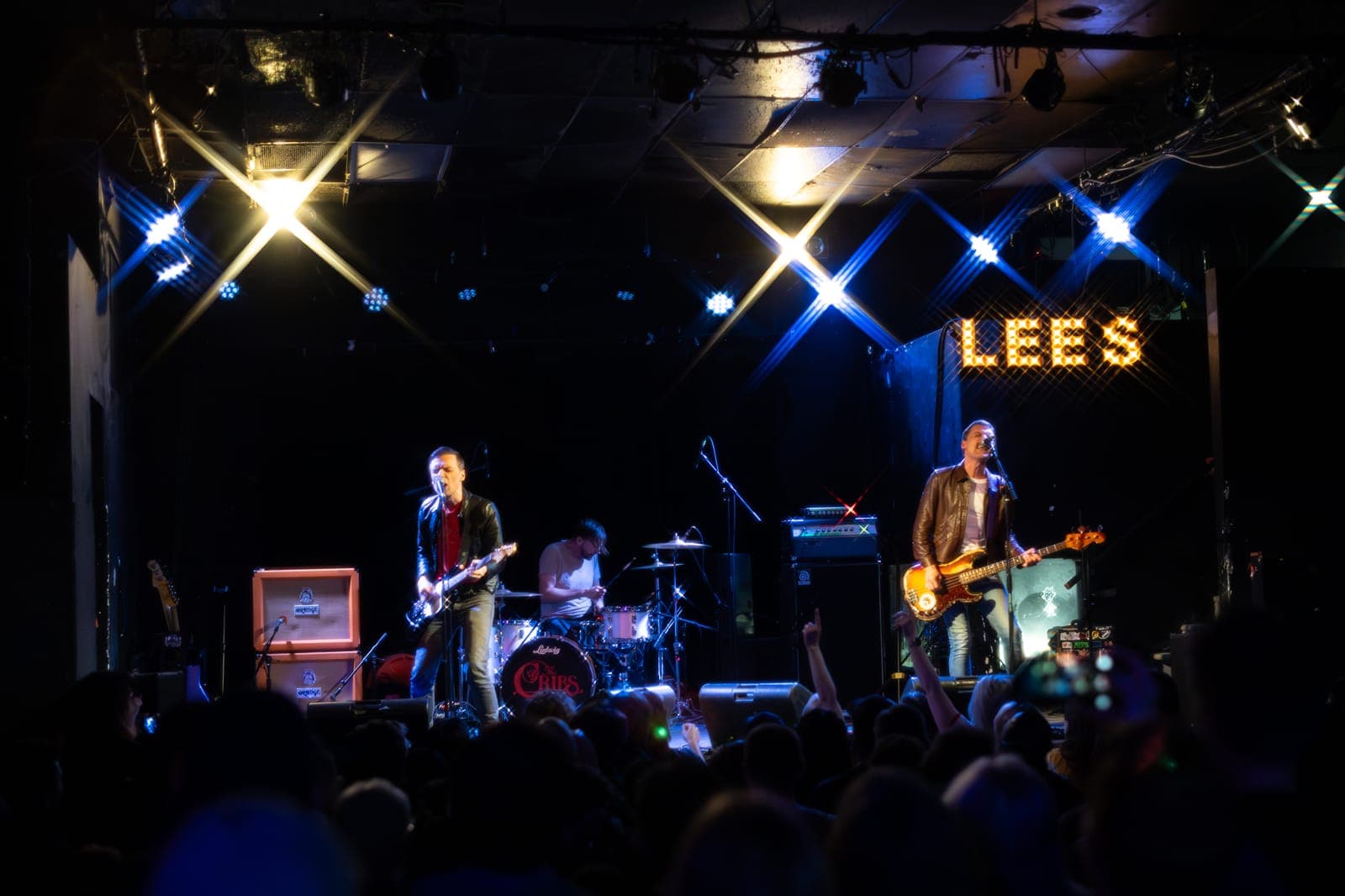 The Cribs play to a packed, hands-raised crowd from the Lee's Palace stage in Toronto, Ross Jarman's 'The Cribs' Ludwig kit centred beneath the 'LEES' marquee