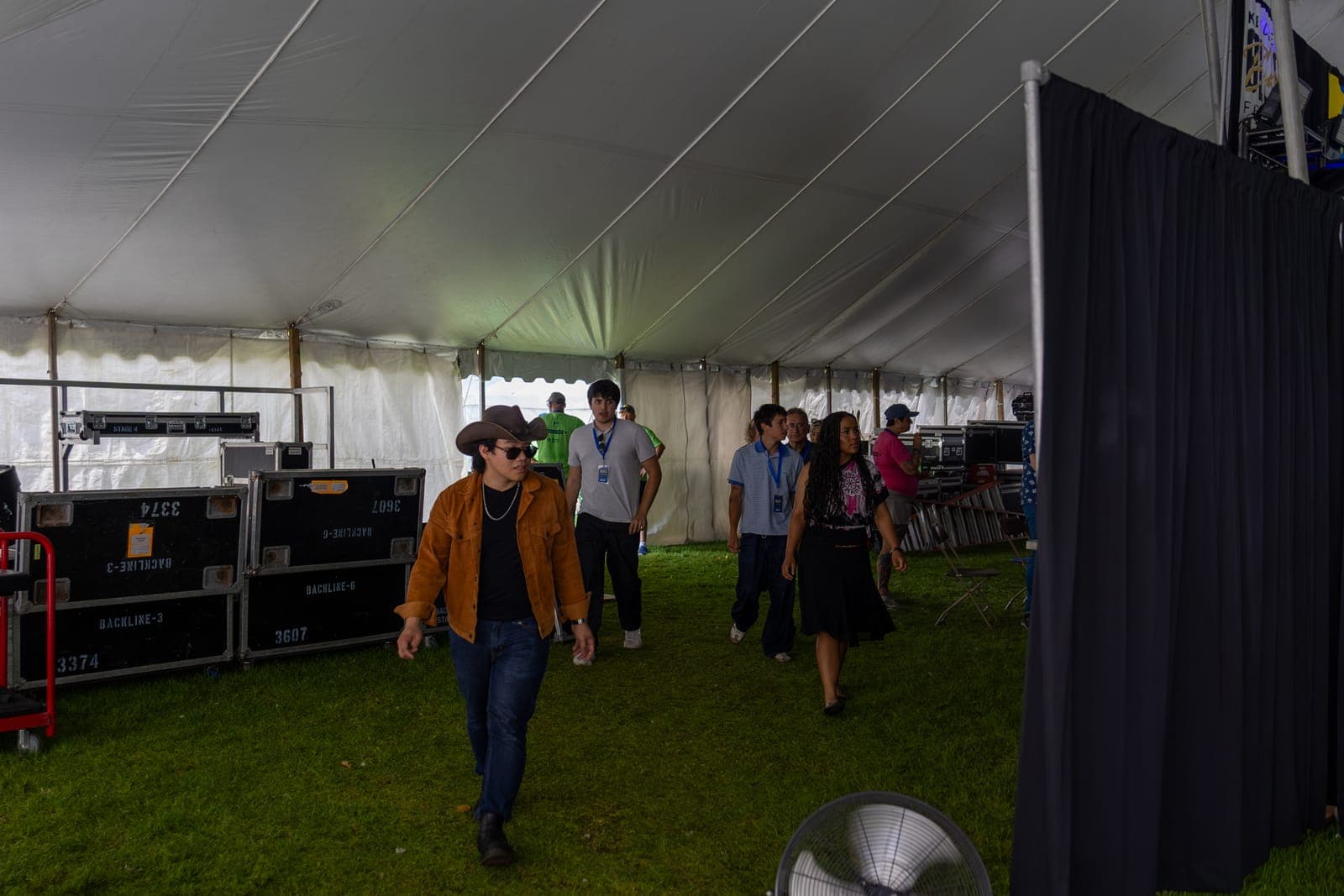 Isy Aboagye's band walks through the backstage at Kitchener Blues Festival, the guitarist leading in a cowboy hat and tan jacket