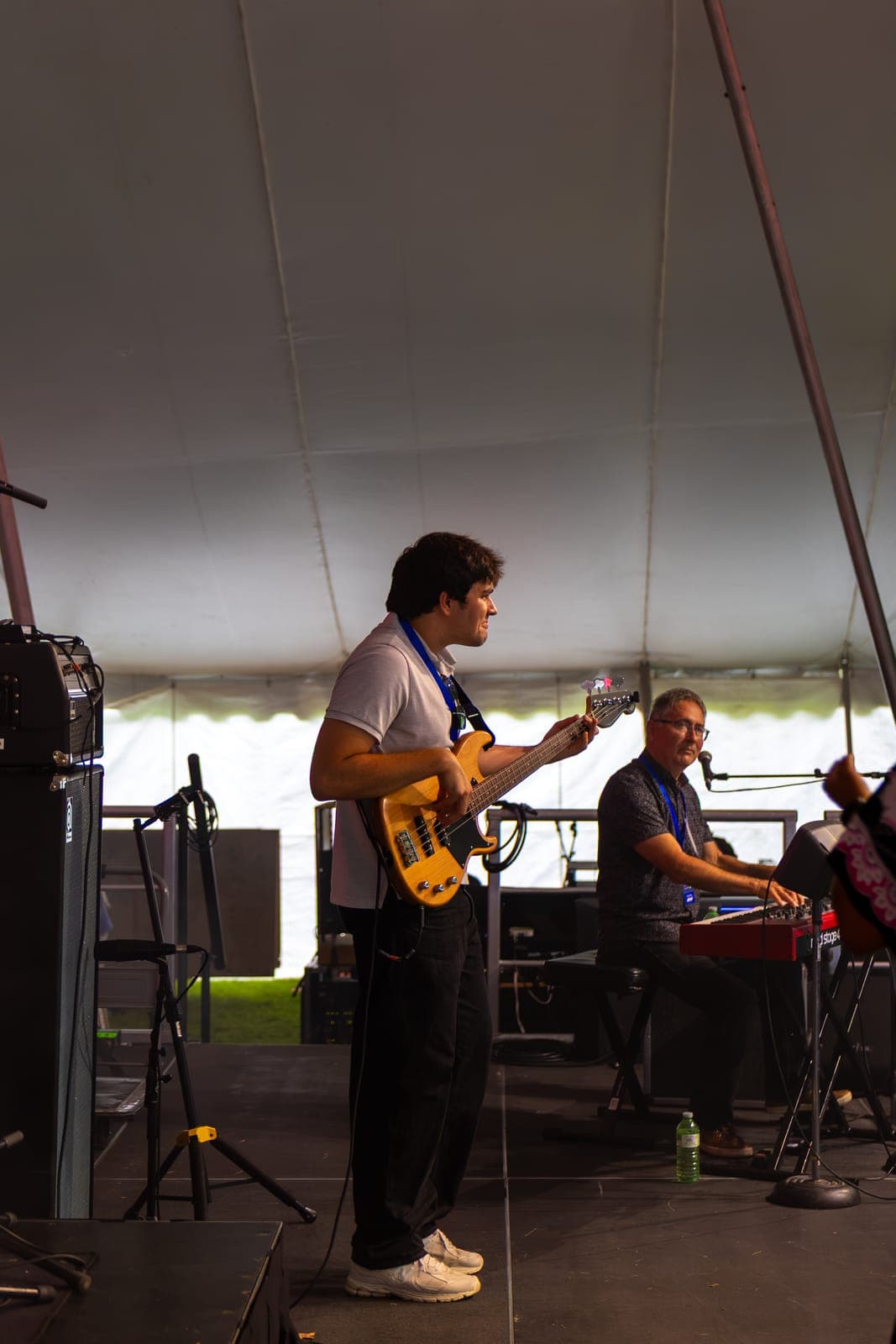 Isy Aboagye's bassist goofs around mid-song at Kitchener Blues Festival, jutting his head back and forth as he plays his natural-finish bass, the keyboardist at his red Nord Stage 4 beside him under the daylit festival tent