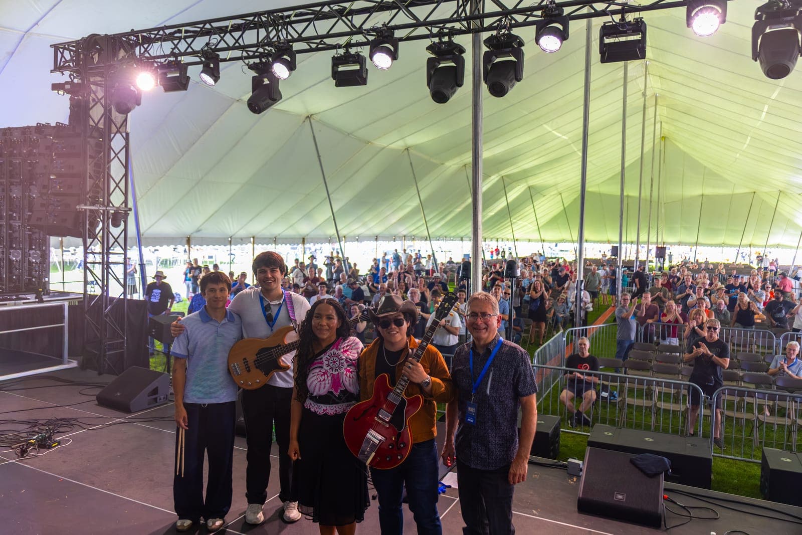 Isy Aboagye and her four bandmates line up for a group photo on stage after their set at Kitchener Blues Festival, the applauding crowd filling the festival tent behind them