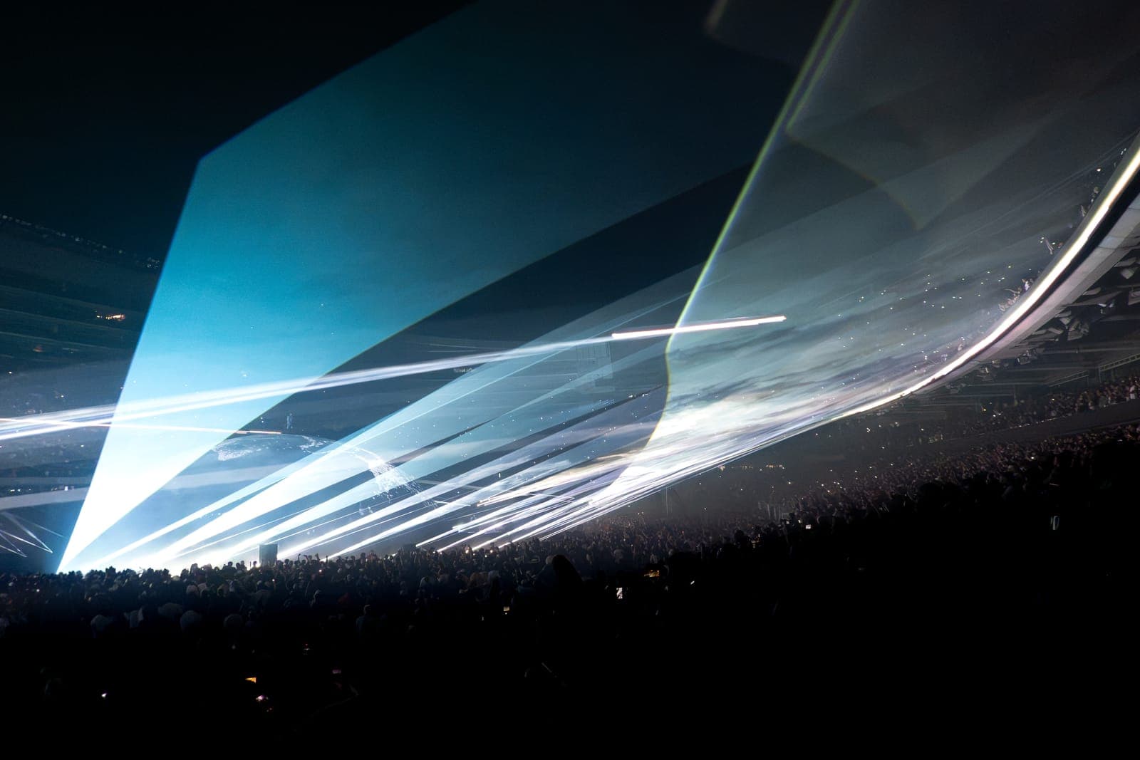 Teal and white planes of laser light sweep low over the silhouetted crowd at Soldier Field