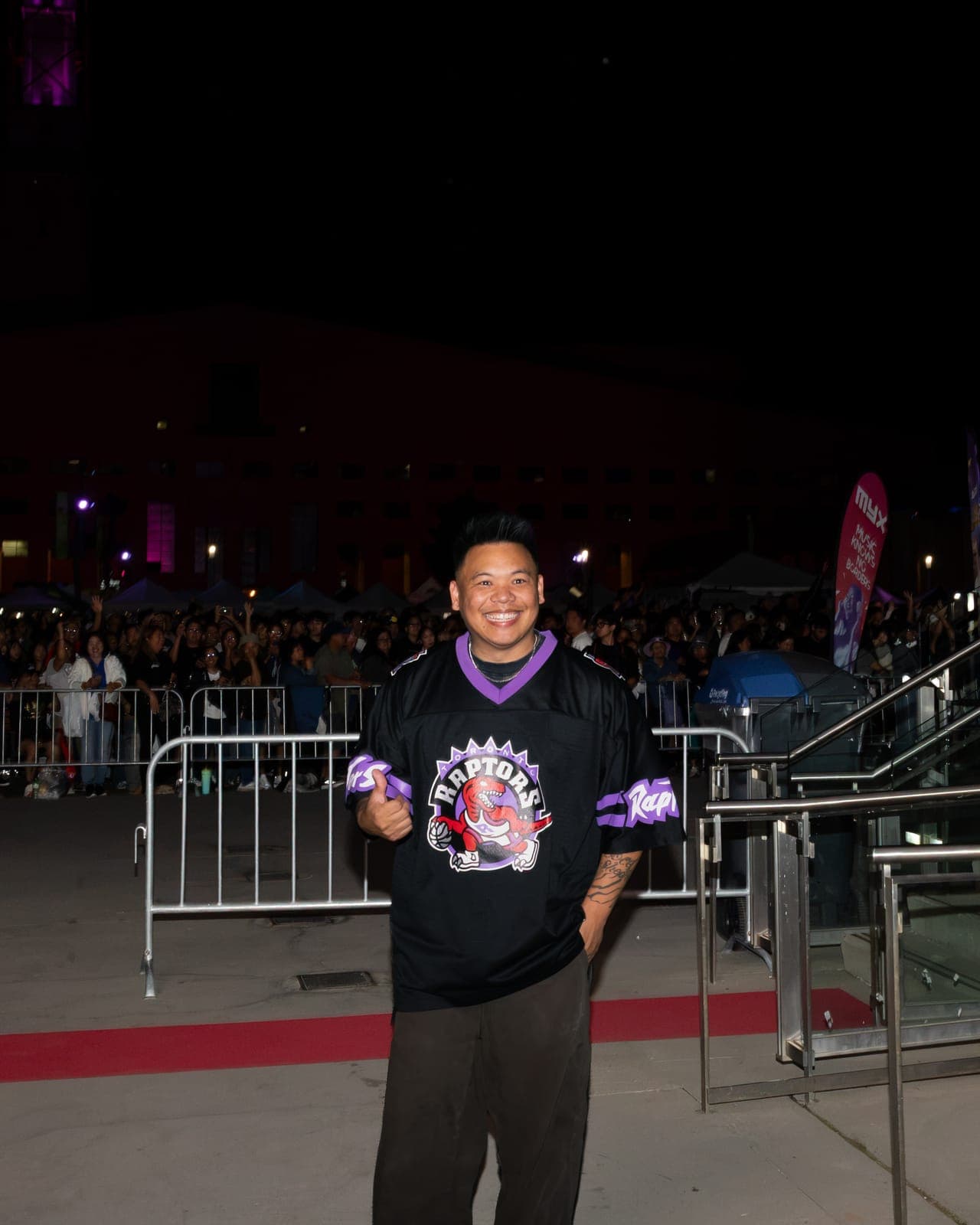 AJ Rafael gives a thumbs up on the red carpet in his Raptors jersey, the barricaded crowd waiting behind him at Mississauga Celebration Square