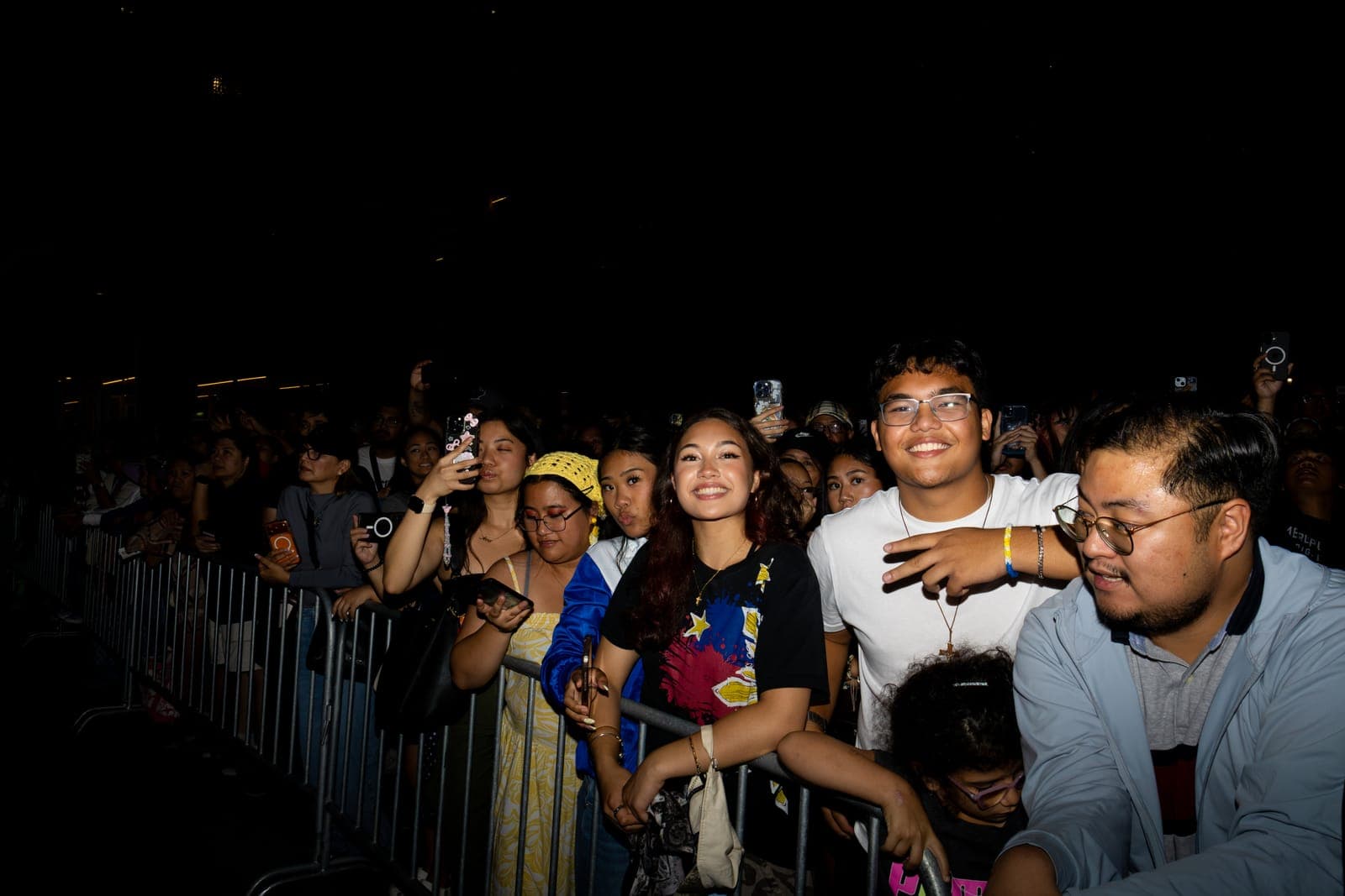 Fans press against the front barricade at Philippine Festival Mississauga, one in a tee splashed with the Philippine flag, phones held overhead