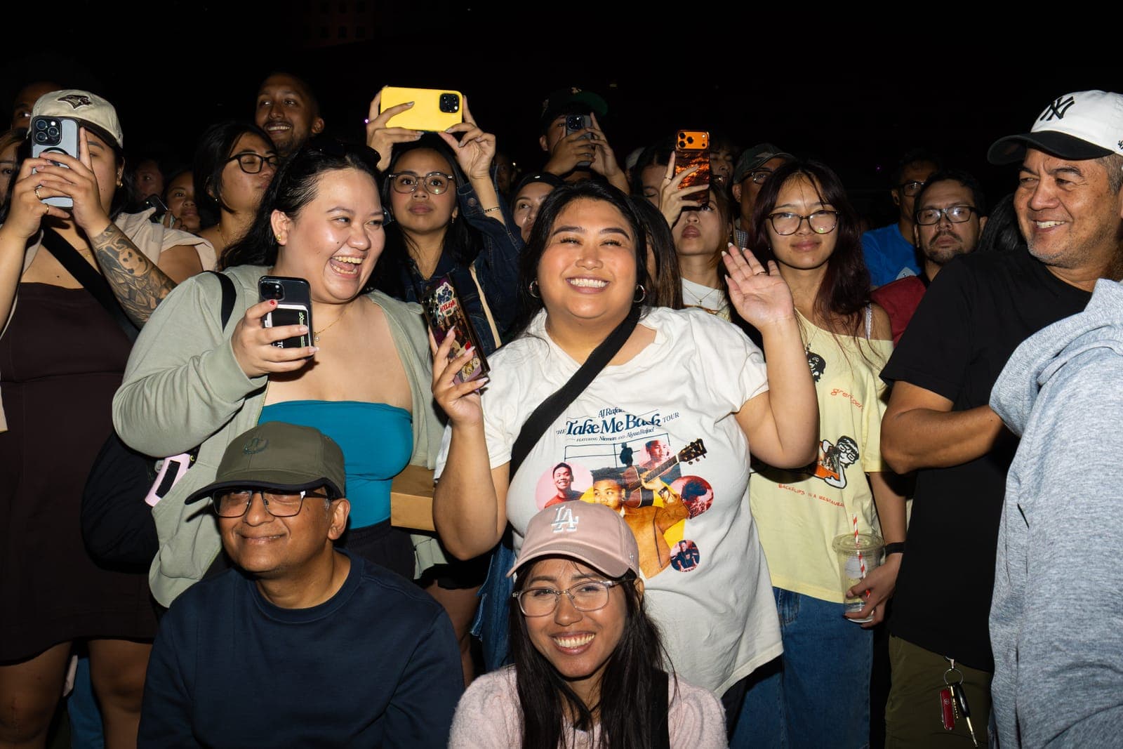 A fan in an AJ Rafael 'Take Me Back' tour shirt waves and beams from the crowd at Mississauga Celebration Square