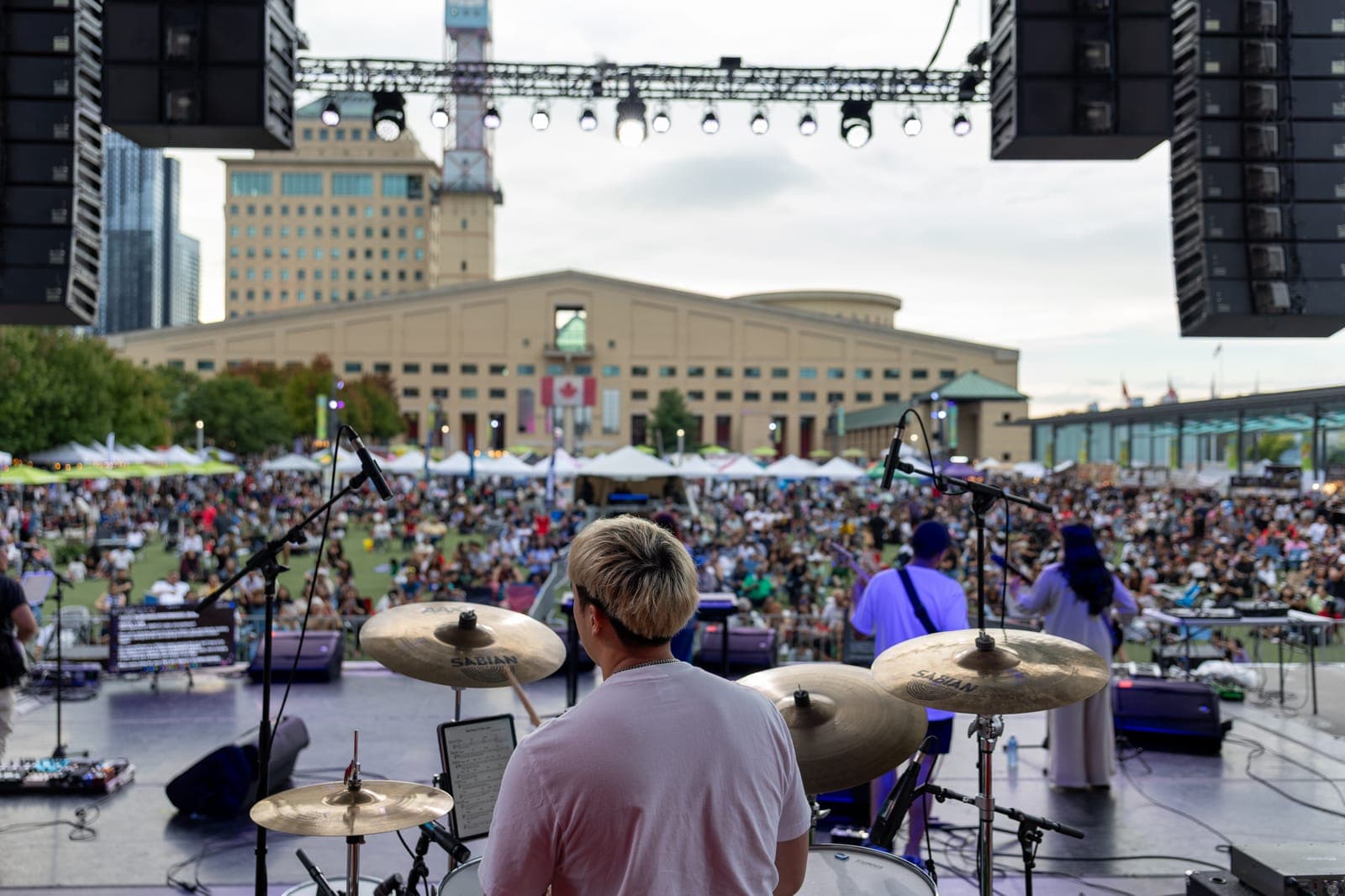 A view over the shoulder of Simplé's drummer out across Mississauga Celebration Square, the afternoon crowd filling the lawn in front of the Civic Centre