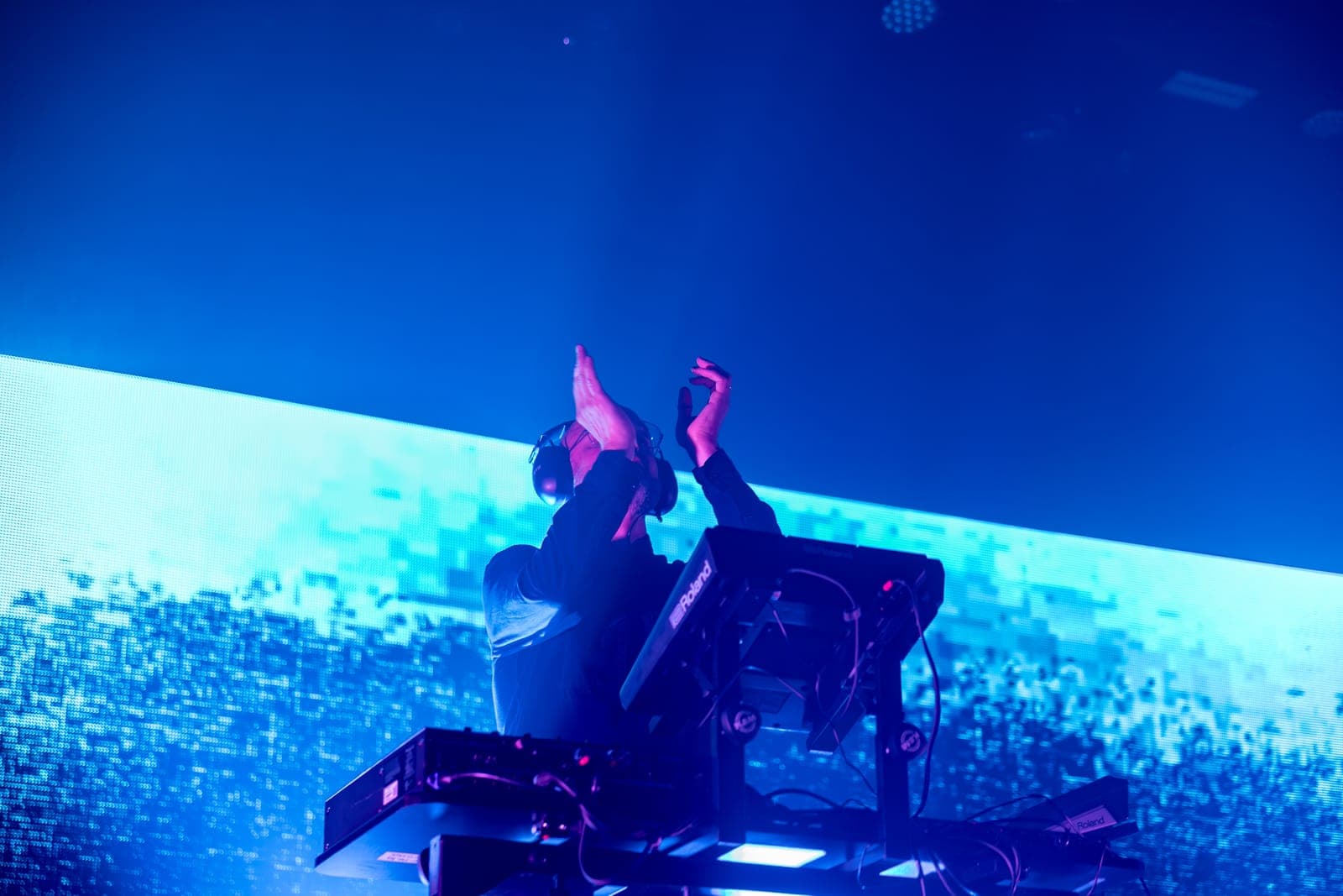 Tinlicker's Micha Heyboer raises both hands above the decks against a vast blue LED wall at HISTORY Toronto