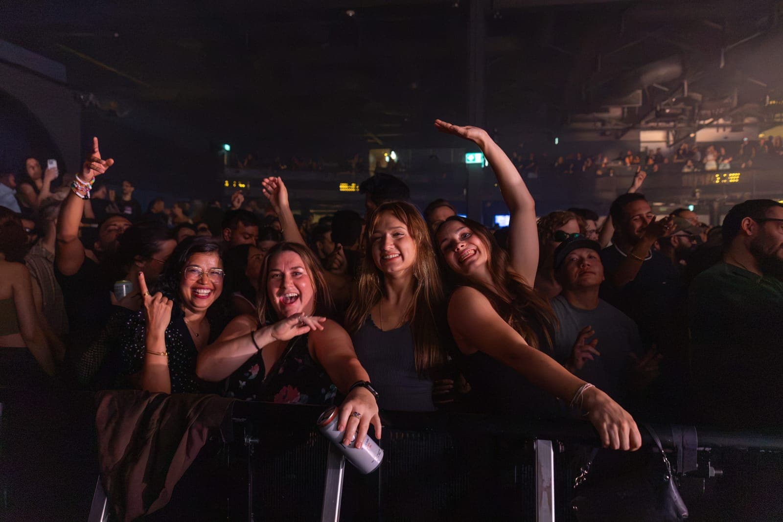 Four friends grin over the barricade at HISTORY, the venue's balcony filled behind them for Tinlicker