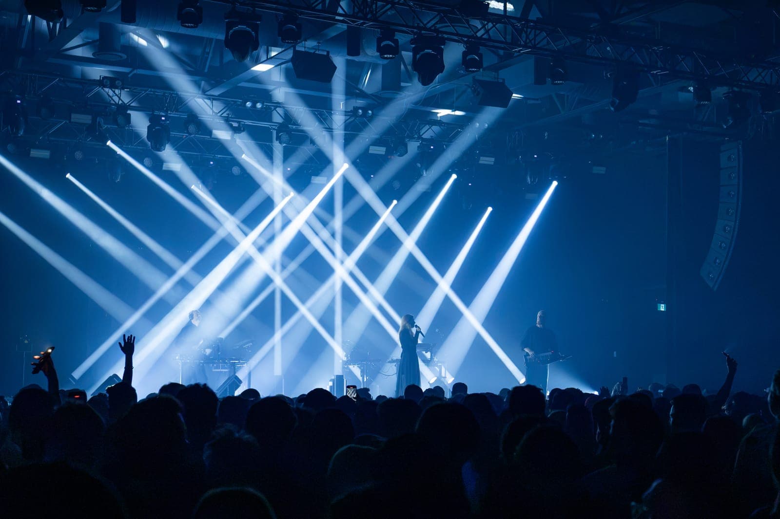 A wide view over the crowd at HISTORY as white beams cross above Tinlicker's stage, the vocalist at the centre mic