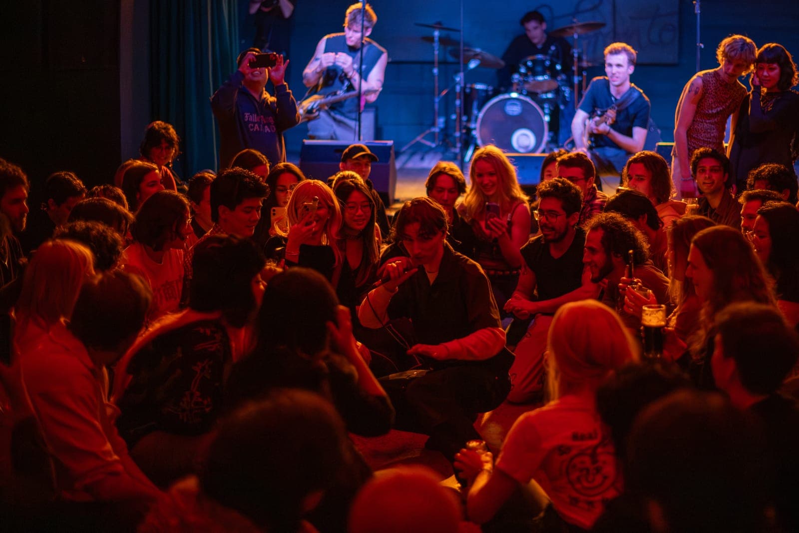 Black Pontiac play to a crowd seated on the floor during an intimate, red-lit moment at The Drake Underground