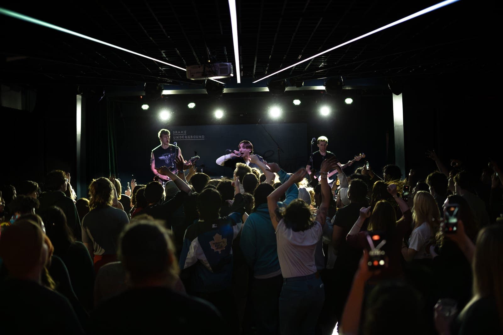 Black Pontiac silhouetted against bright stage lights as the packed Toronto crowd films on their phones at The Drake Underground