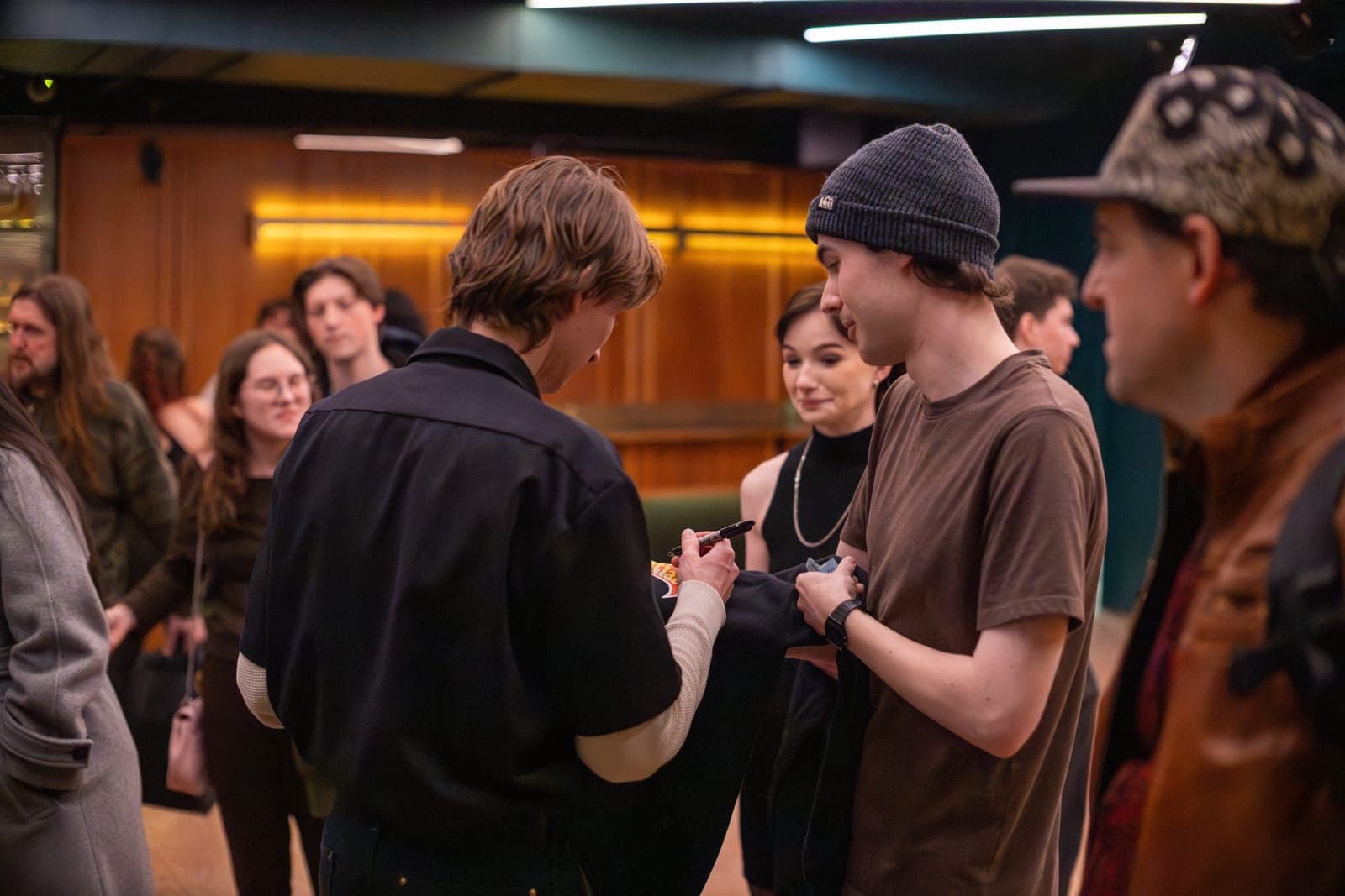 A Black Pontiac bandmate signs an autograph for a fan in a beanie after the show at The Drake Underground, Toronto