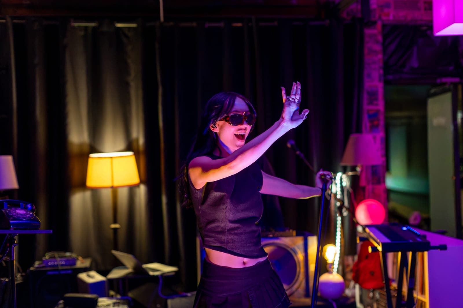 City Builders' vocalist in sunglasses throws an arm up mid-line among table lamps on the DIY stage at Division 88, Toronto