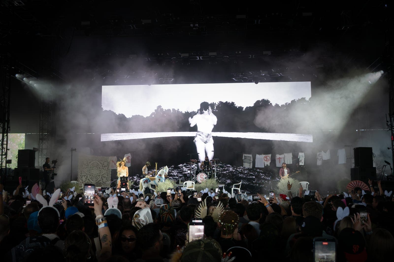 Slayyyter leaps mid-air, silhouetted against a bright screen and smoke at Coachella, Empire Polo Club in Indio