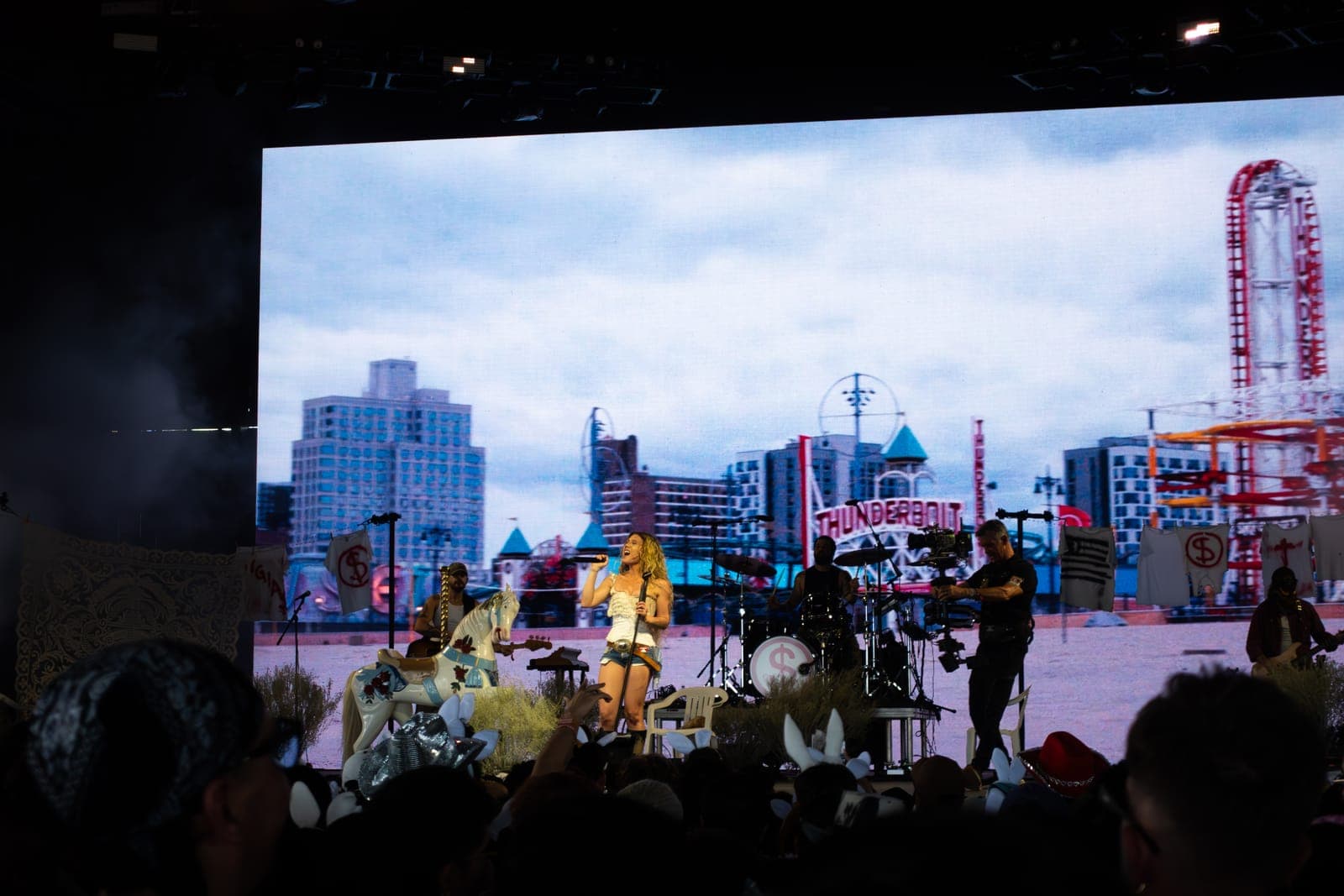 Slayyyter performs on a beach-themed set with a Coney Island backdrop as fans in bunny ears watch at Coachella, Indio