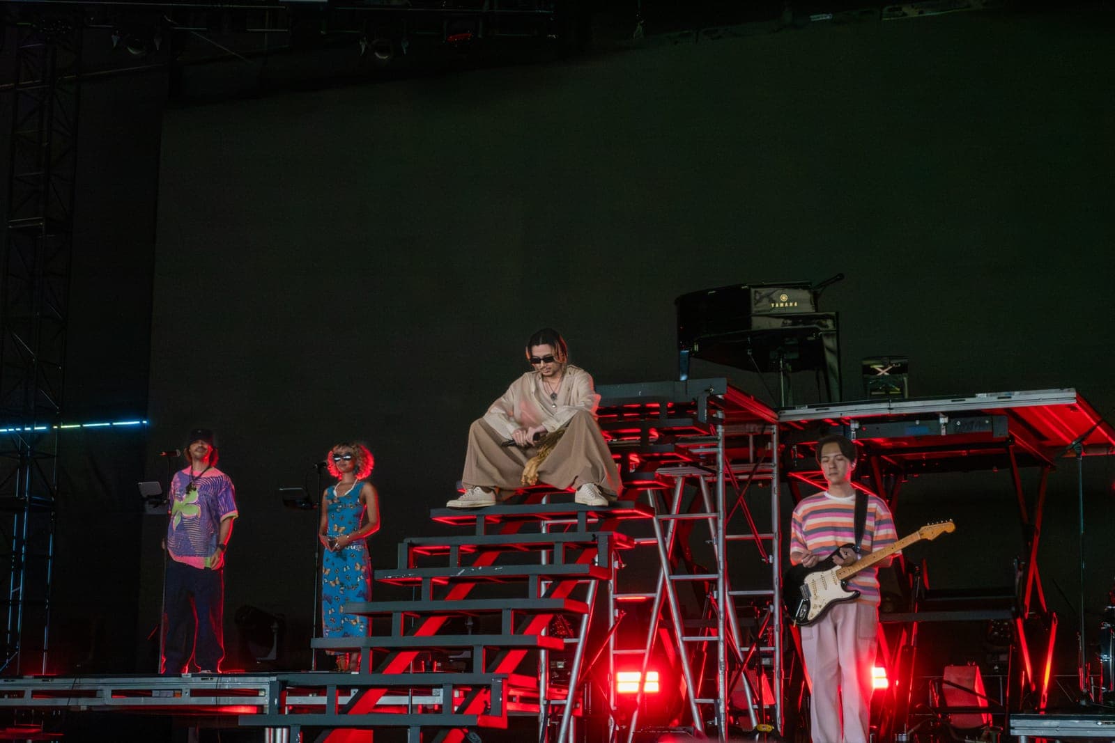 Fujii Kaze perched on the red-lit riser steps beside his band at Coachella, Empire Polo Club in Indio
