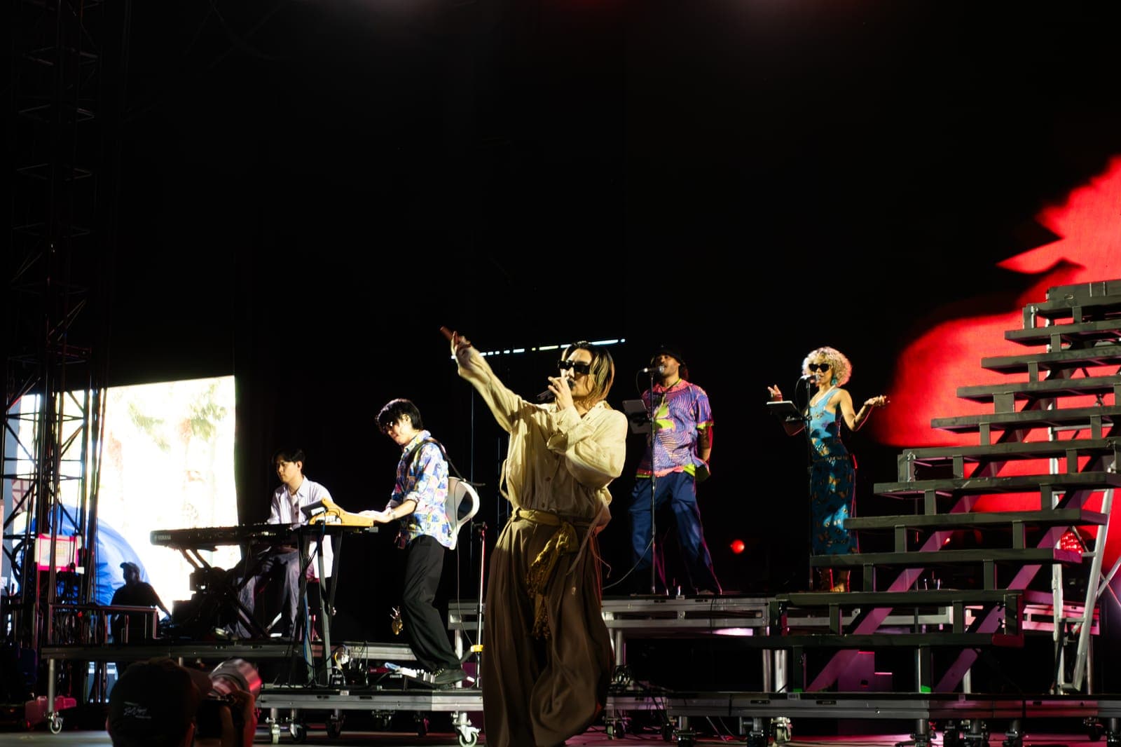Fujii Kaze gestures mid-song with his band spread across the stepped stage at Coachella, Indio