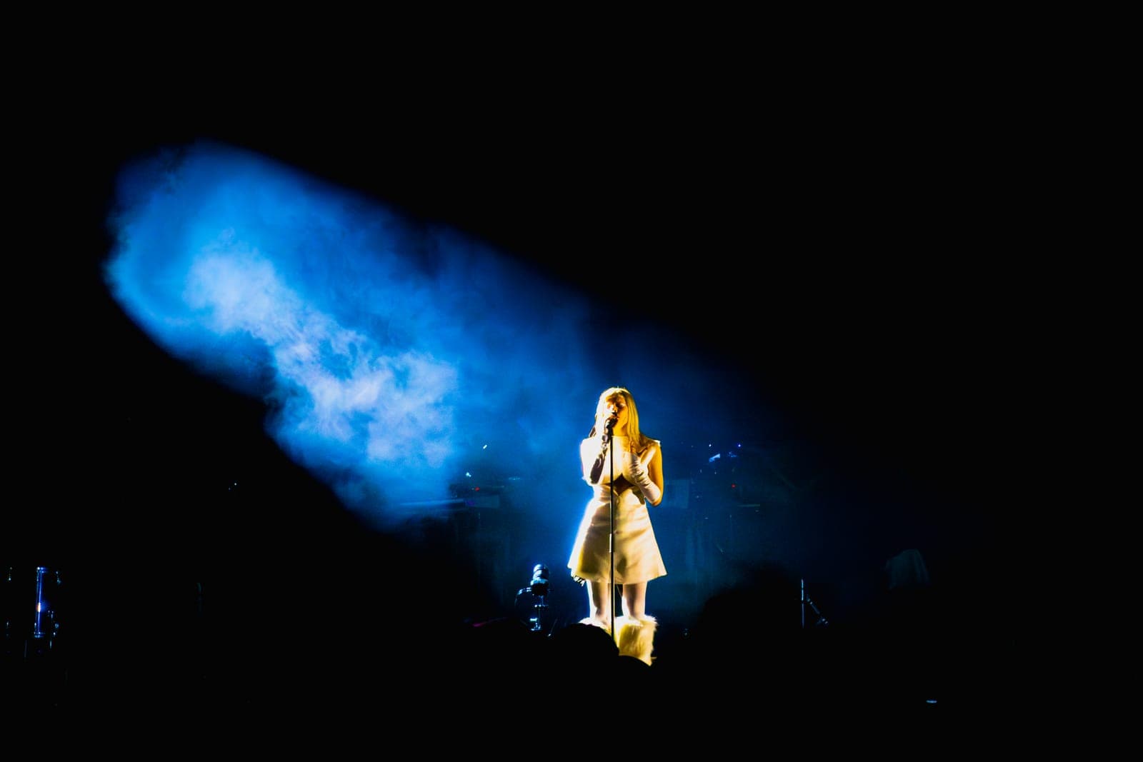 Tomora lit by a diagonal blue spotlight cutting through the haze at Coachella, Indio