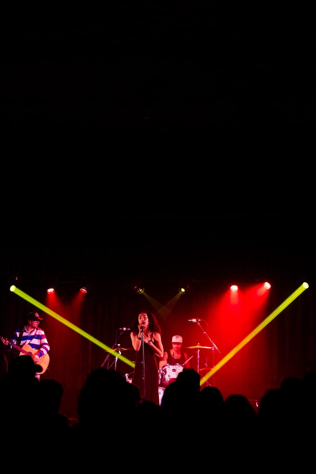 Nia Nadurata performs centre stage with her band as green laser beams cut across the red-lit room at Longboat Hall, Toronto