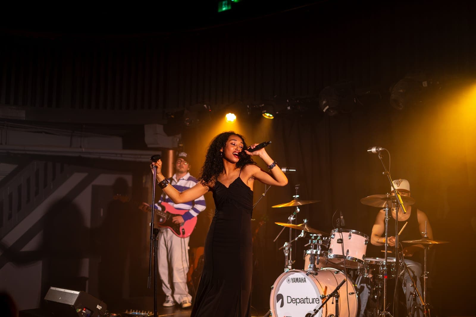 Nia Nadurata belts into the mic in a black gown under warm gold light at Longboat Hall in Toronto
