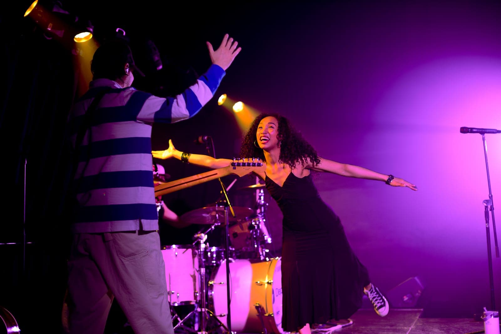 Nia Nadurata laughs with arms outstretched, sharing a moment with her guitarist under purple light at Longboat Hall, Toronto