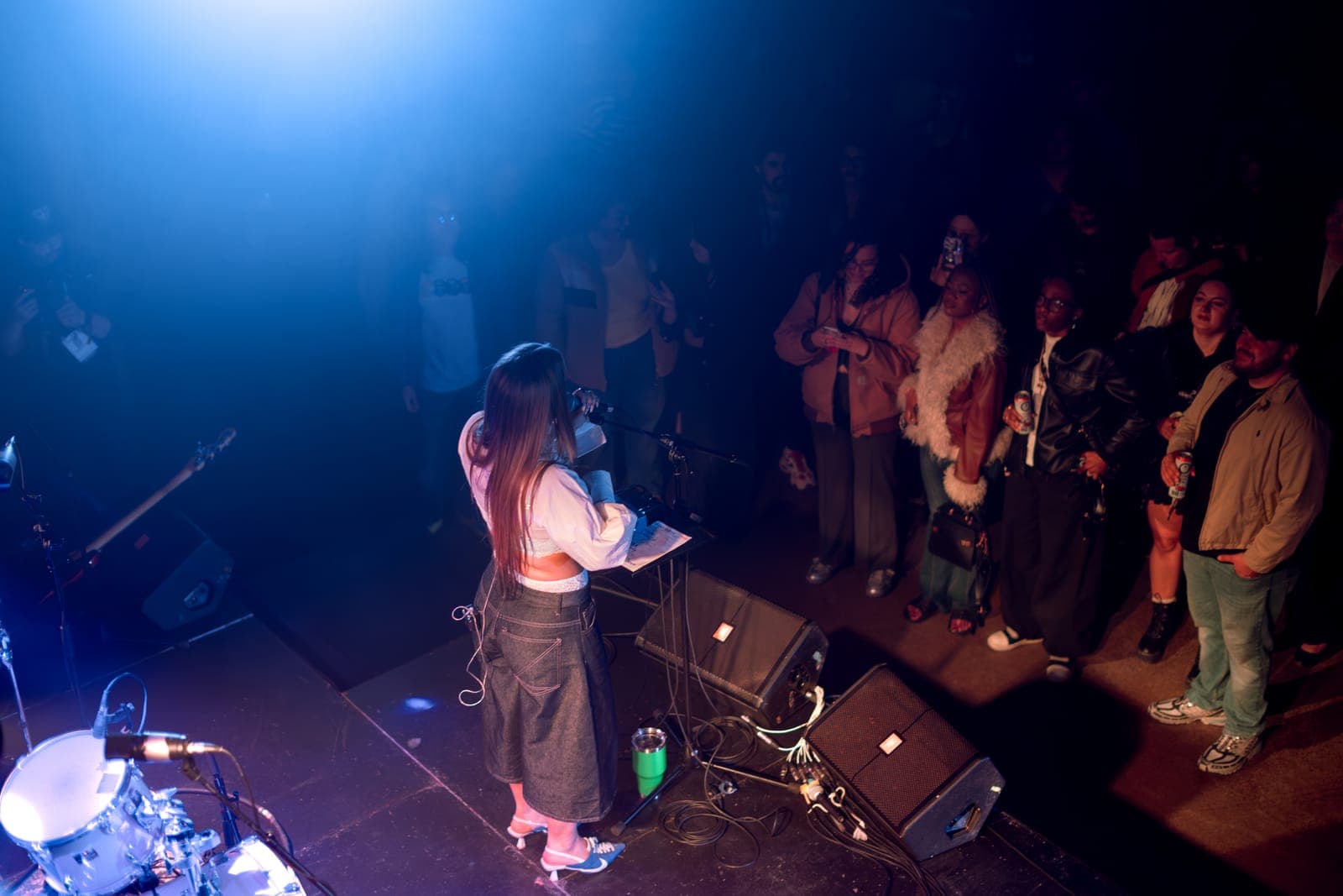 Puma June addresses an intimate crowd gathered at the stage edge under a blue wash at Longboat Hall in Toronto