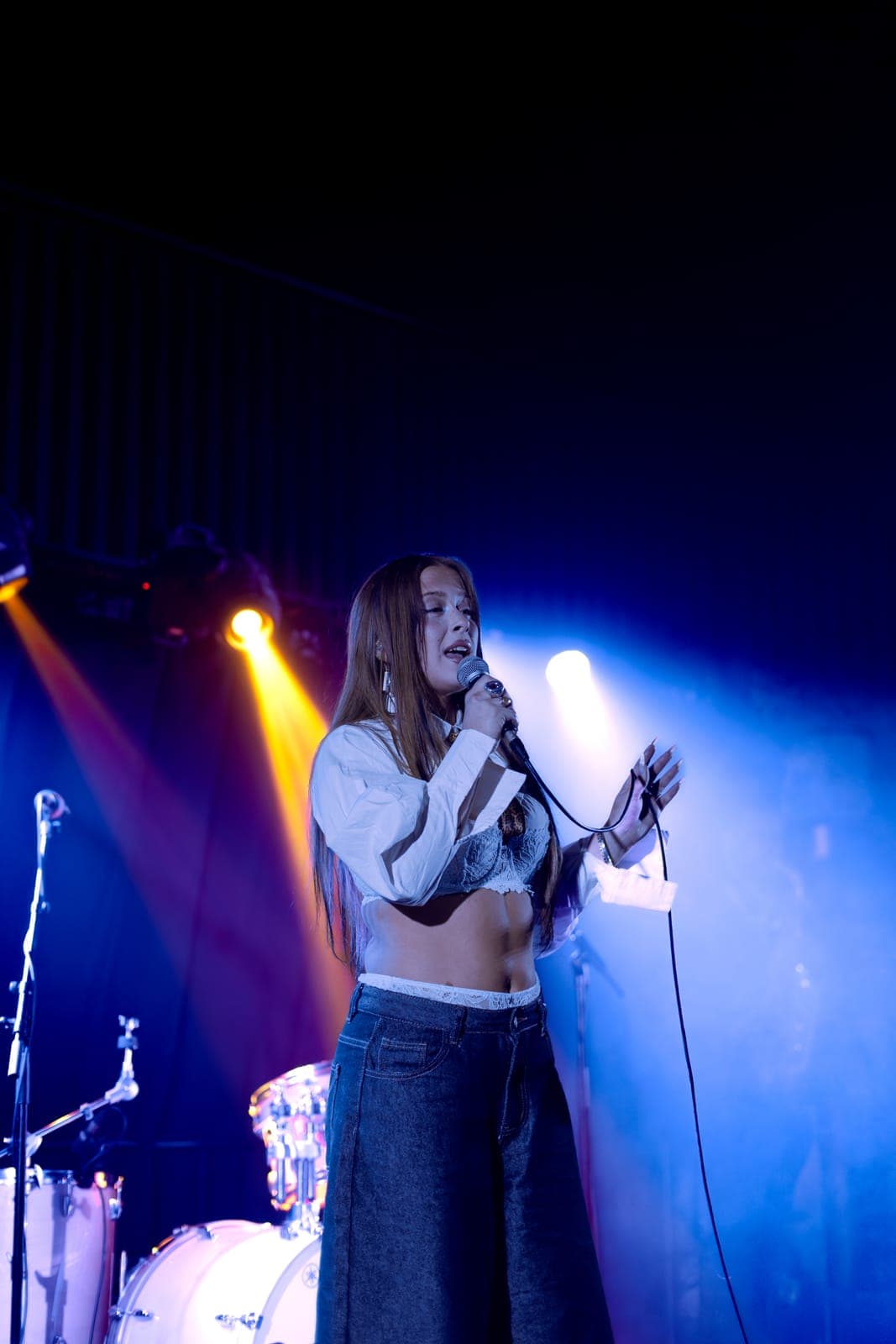 Puma June performs in white over lace, split by blue and amber light at Longboat Hall in Toronto
