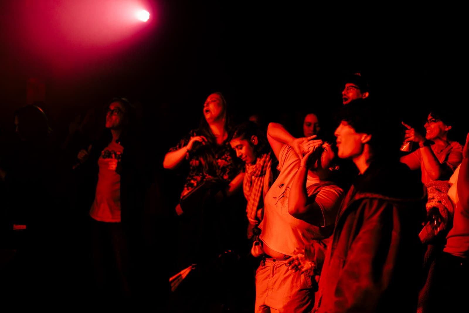 Fans sing and dance in the red-lit crowd during Cherry Kim's set at Longboat Hall in Toronto