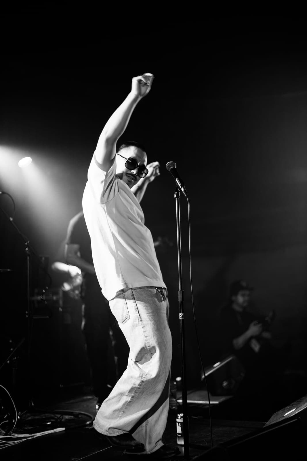 Black-and-white frame of Cherry Kim reaching skyward at the mic at Longboat Hall, Toronto