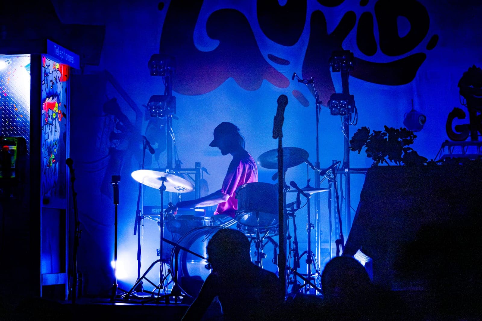 Good Kid's drummer silhouetted in blue light beneath the band's painted backdrop at Danforth Music Hall, Toronto