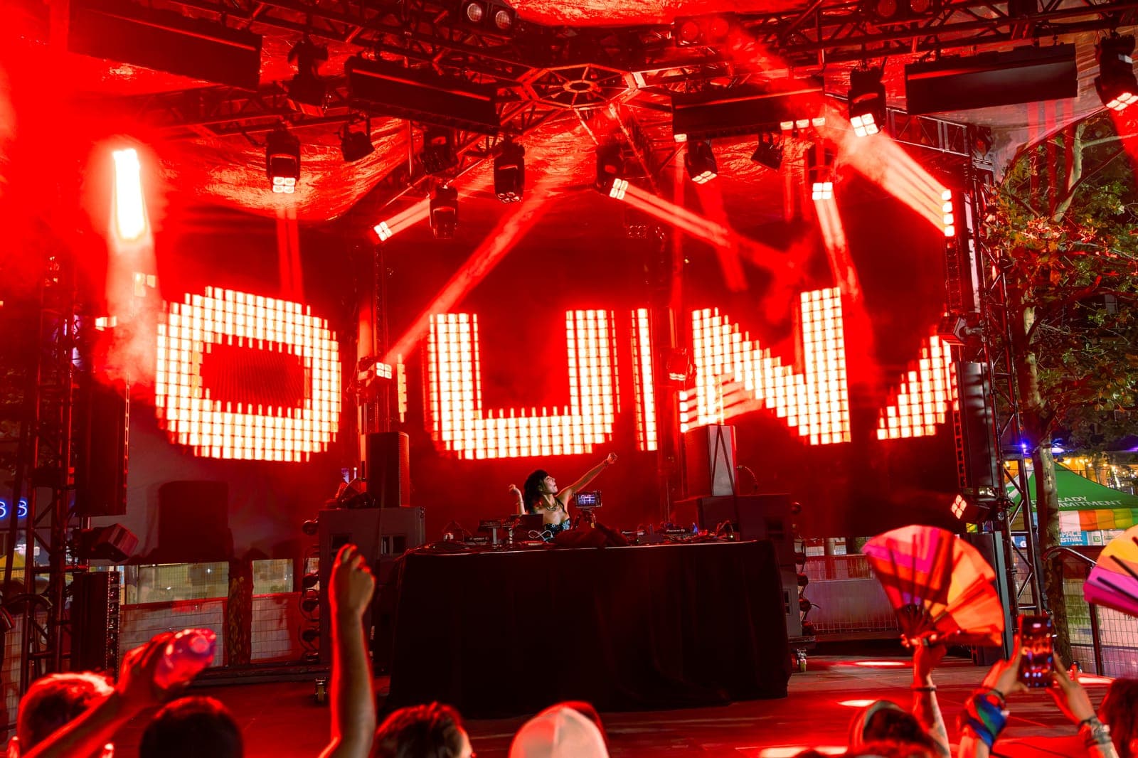 Youna reaches an arm out under drenching red light as her name glows in giant illuminated block letters behind the stage.