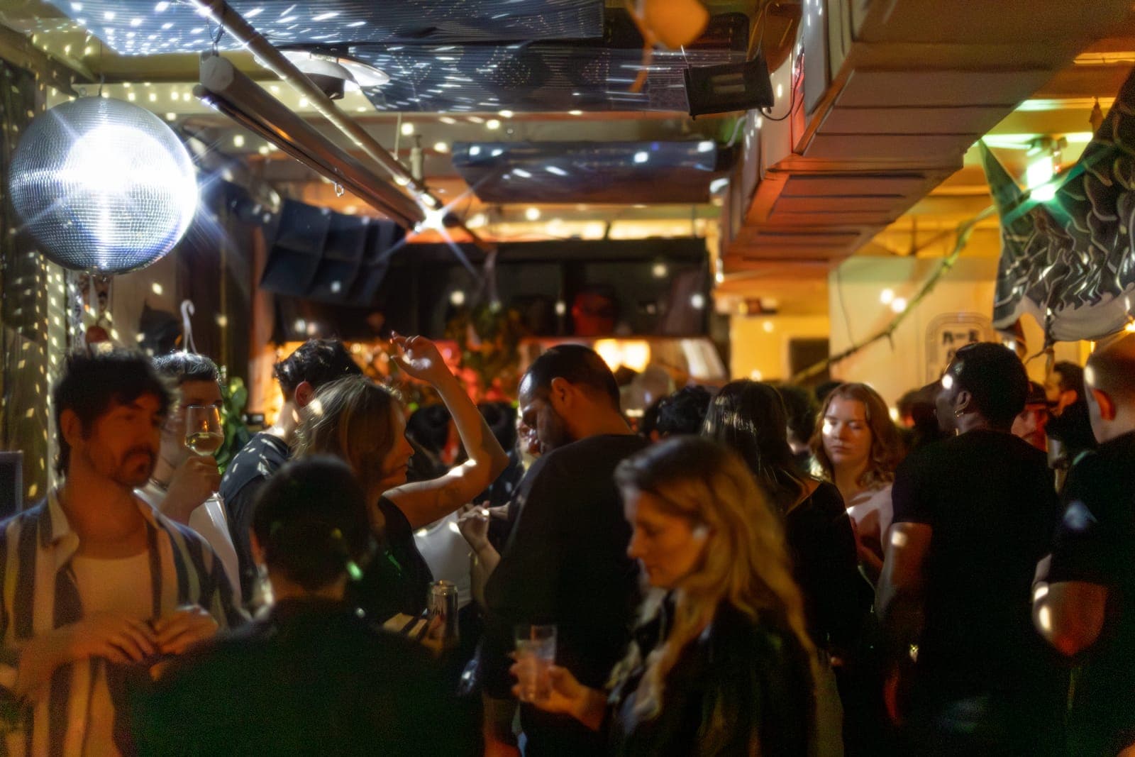 Partygoers mingle with drinks beneath a disco ball and fairy lights at 915 Dupont in Toronto