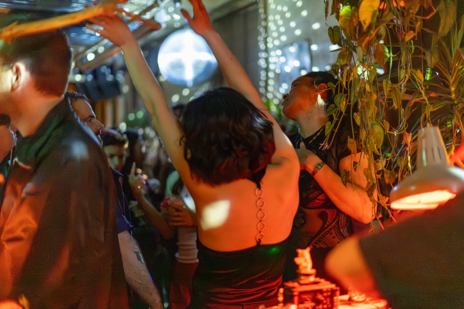 A dancer throws her arms up under the disco ball among the crowd at 915 Dupont in Toronto