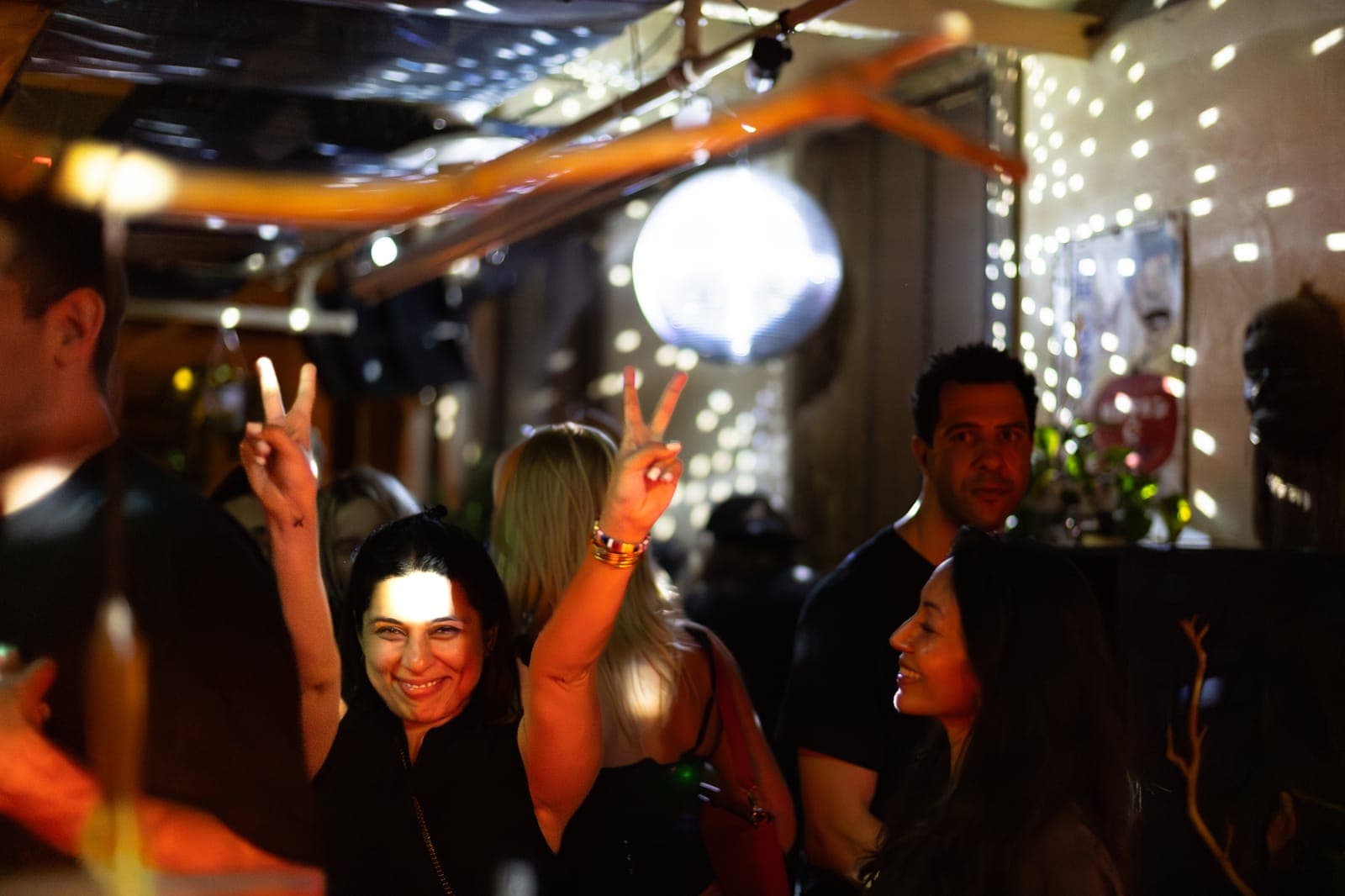 Friends flash peace signs and smile under the disco ball at 915 Dupont in Toronto