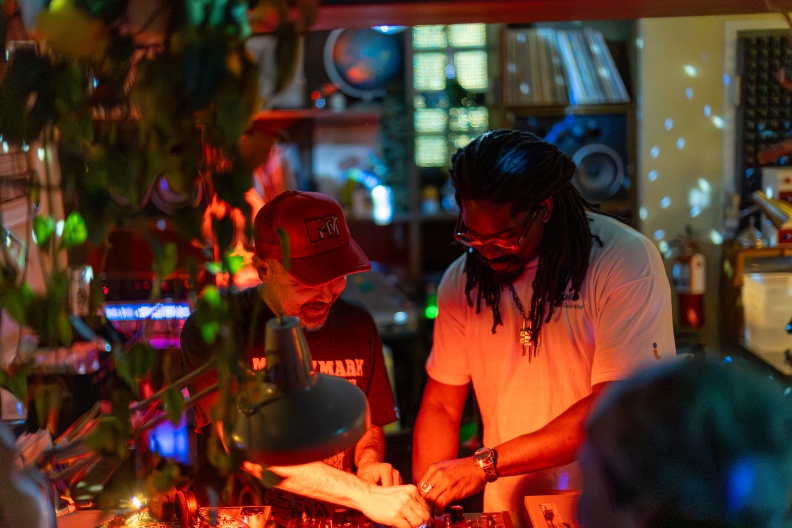 DJs Do Not Push and Kiinjo work the turntables together amid plants and red light at 915 Dupont in Toronto