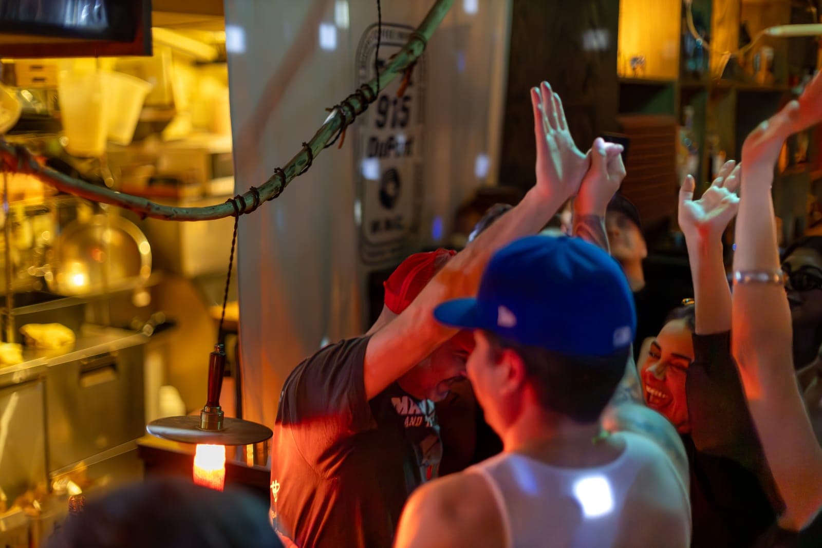 The crowd throws their hands up by the booth beneath the 915 Dupont sign in Toronto