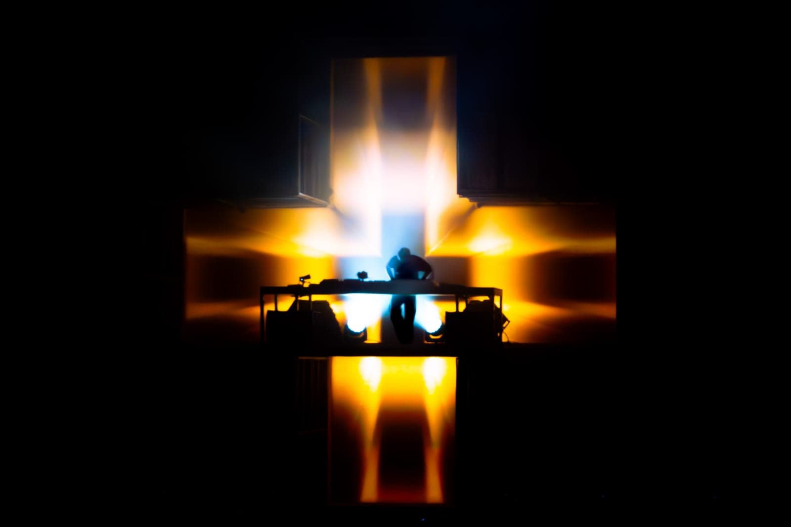 Martin Garrix silhouetted at the cross-shaped stage with a shaft of light rising behind him at RBC Amphitheatre, Toronto