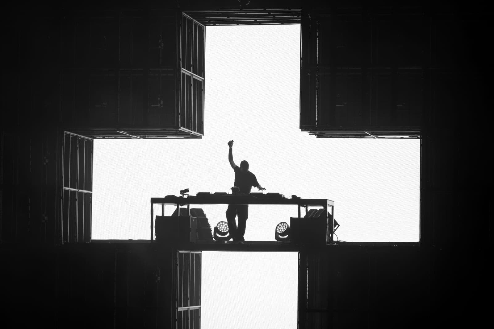 Martin Garrix raises a fist, silhouetted in the cross-shaped stage against a blinding white screen at RBC Amphitheatre in Toronto