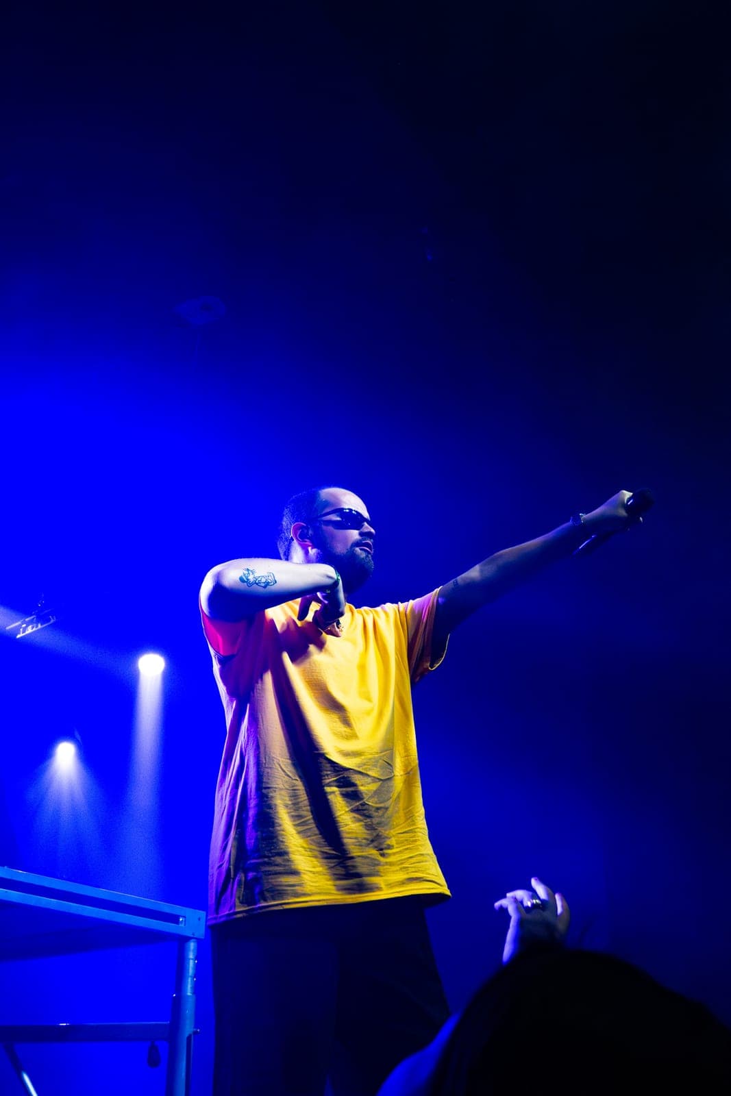 Myd points out to the crowd, arm extended, under blue light at The Mod Club in Toronto
