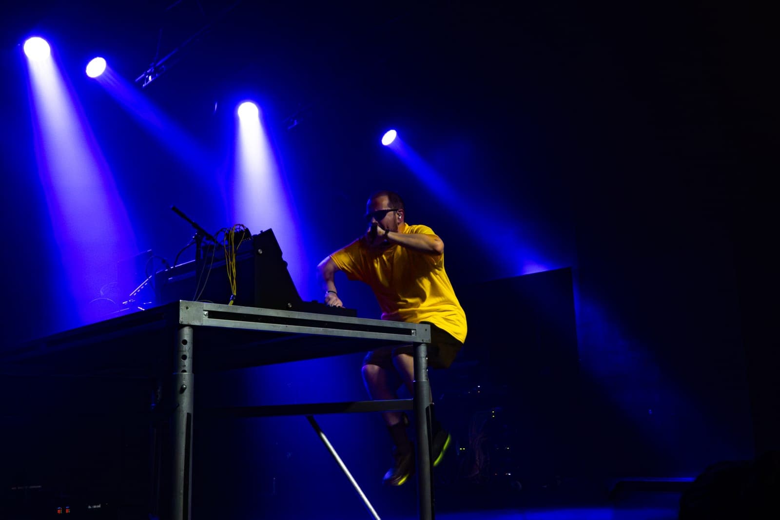 Myd clambers over his equipment table mid-set in a yellow tee at The Mod Club, Toronto