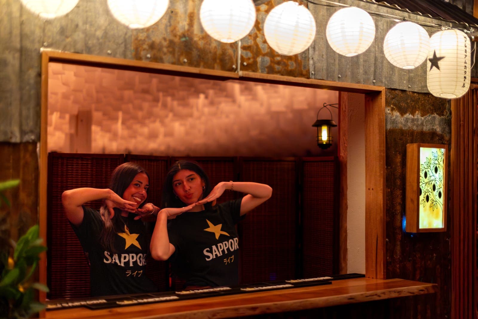 Two attendees in Sapporo tees pose under paper lanterns at the Sapporo Live: Lemon Sour Experience at Standard Time in Toronto