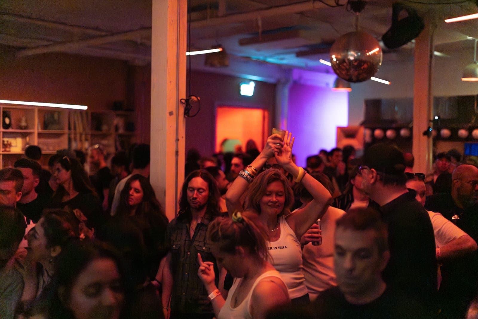 The crowd dances beneath a disco ball in the warm-lit room at the Sapporo Live night at Standard Time in Toronto