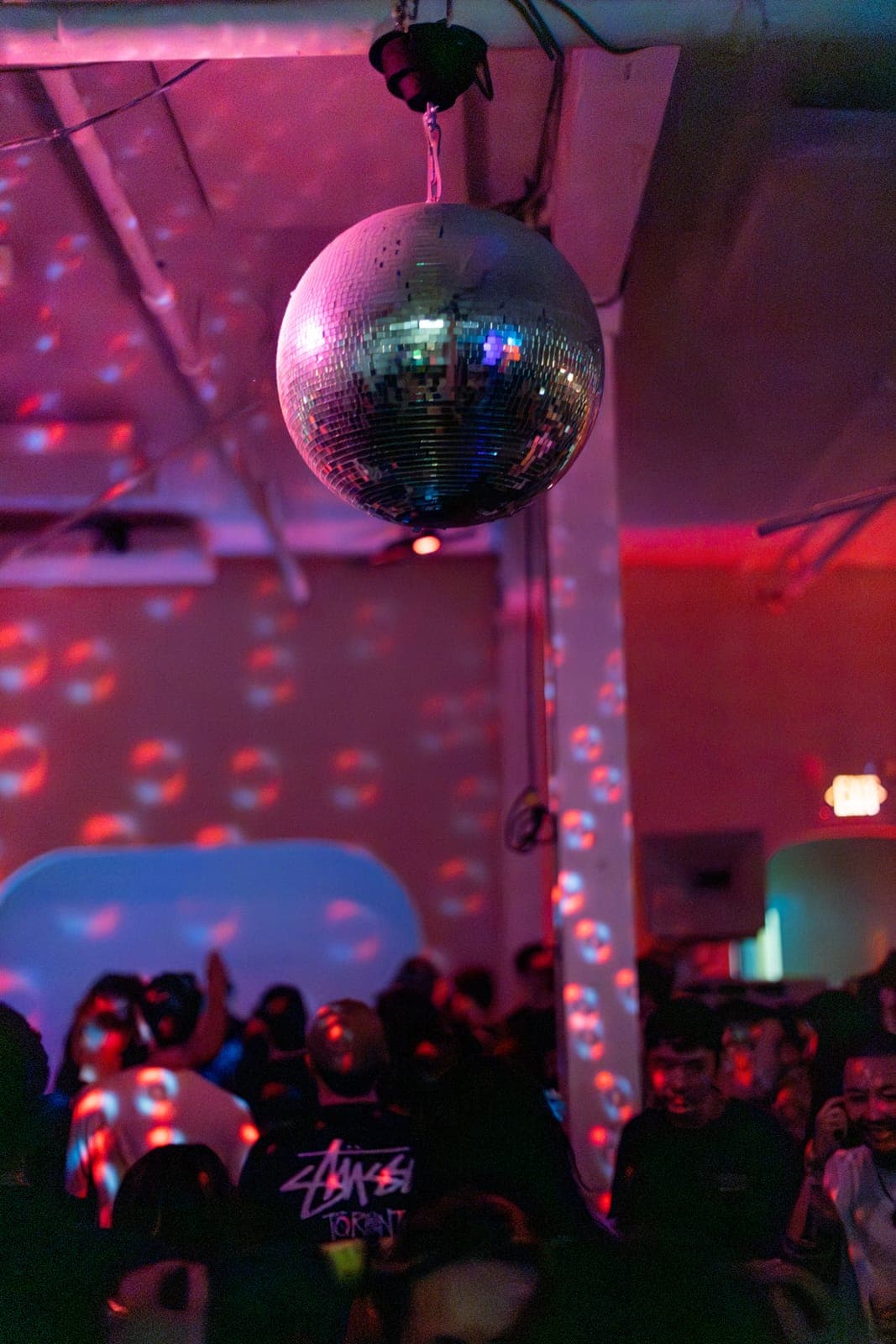 A disco ball scatters pink light over the crowd at the Sapporo Live night at Standard Time in Toronto