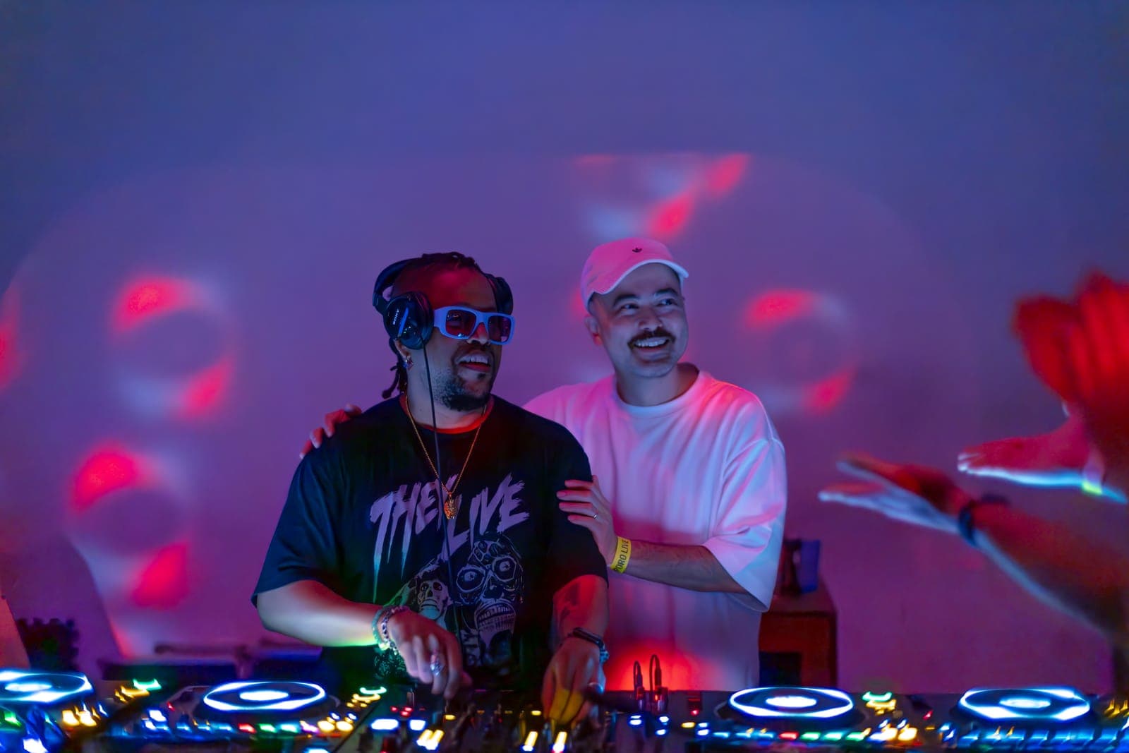 Felix Da Housecat and Kiinjo laugh together behind the decks in pink light at Standard Time in Toronto