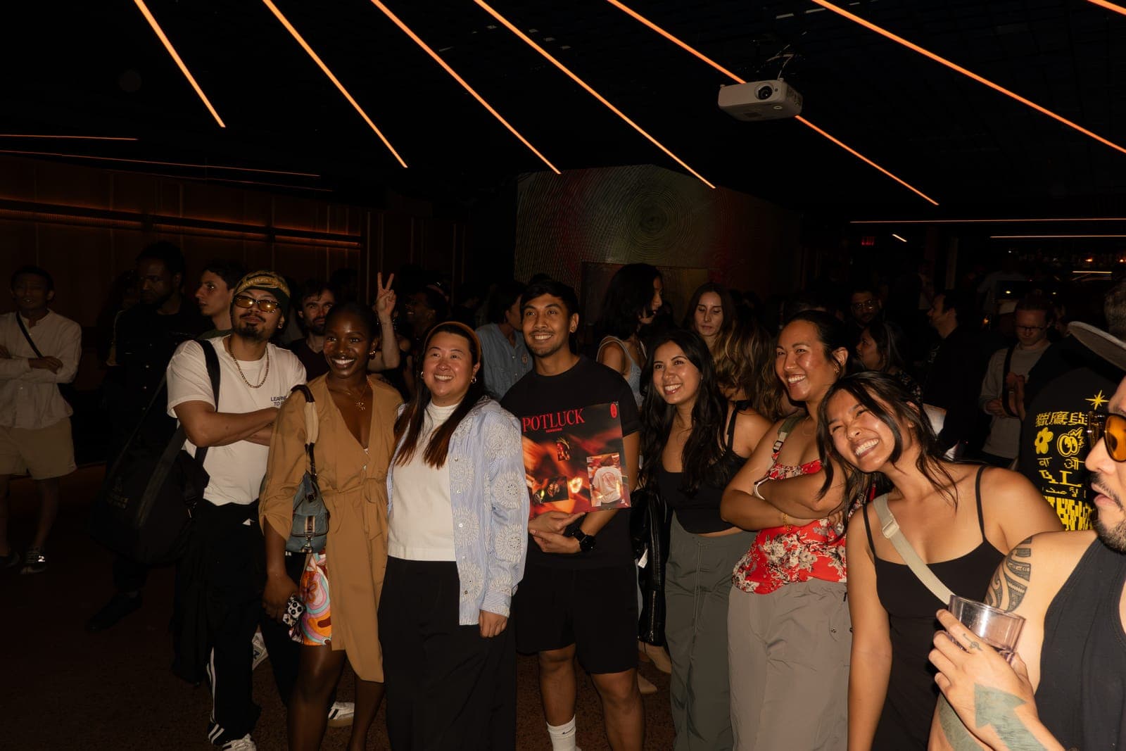 Friends pose with the Potluck Volume 1 record in the lobby of The Drake Underground in Toronto