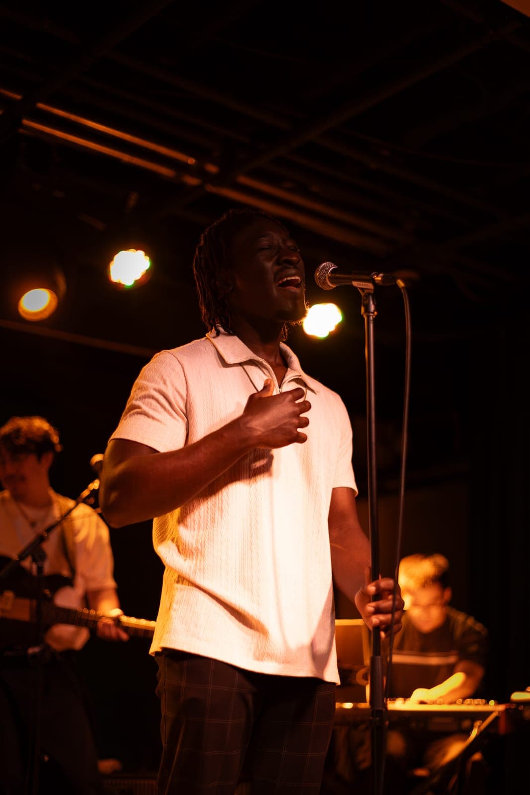 A Takes a Village vocalist sings passionately into the mic with the band behind at The Drake Underground in Toronto