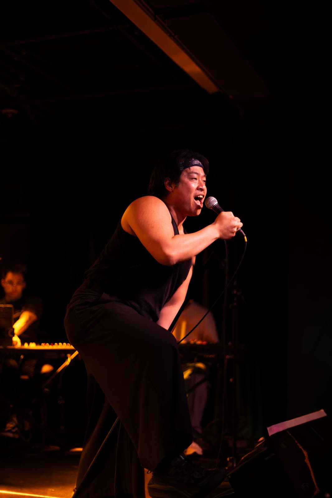 A Takes a Village vocalist in a bandana belts into the mic with a foot on the monitor at The Drake Underground in Toronto