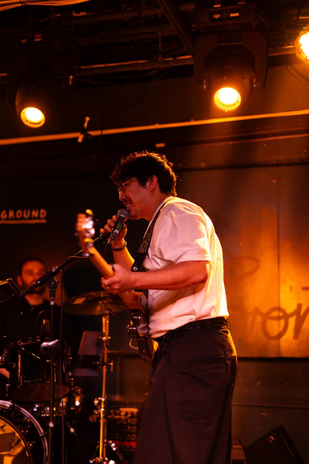 A Takes a Village guitarist sings while playing, the drummer behind him, at The Drake Underground in Toronto